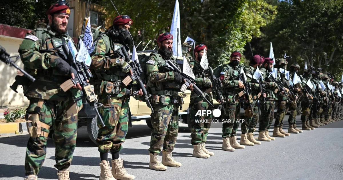 Taliban security personnel in uniform lining up during a military parade in Kabul, Afghanistan, with decorated vehicles and flags visible.