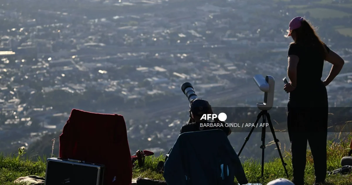 People watch a partial solar eclipse with cameras and special glasses.