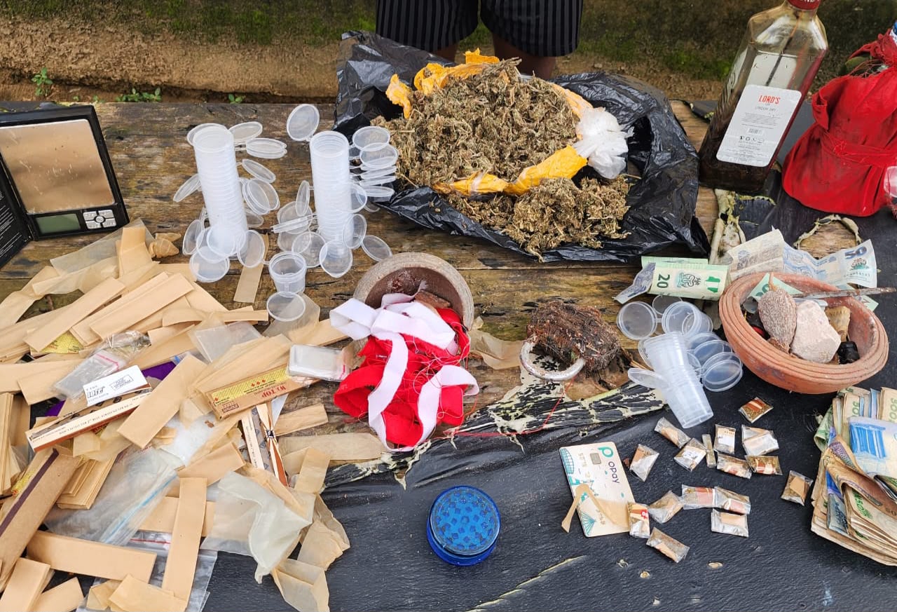 Police officers standing guard over seized illicit substances and cash.